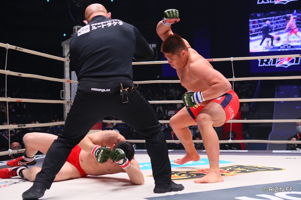 Tsuyoshi Sudario lands a hammerfist punch after dropping Minowaman with leg kicks (© RIZIN FF)