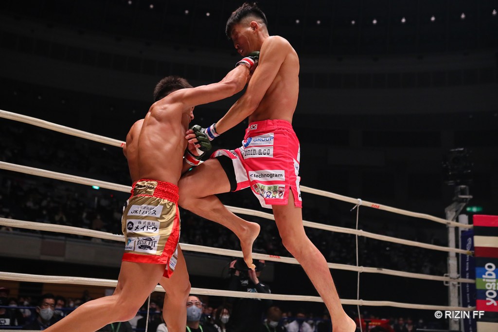 Yutaro Muramoto lands a right hook while Seigo Yamamoto comes forward with a flying knee