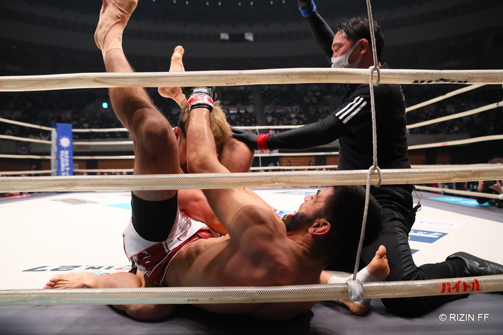 The referee instructs Roberto Satoshi Souza to let go of his triangle choke after Kazuki Tokudome tapped out