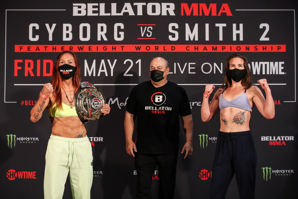Wearing masks, Cris Cyborg and Leslie Smith make fist poses at ceremonial weigh-ins.