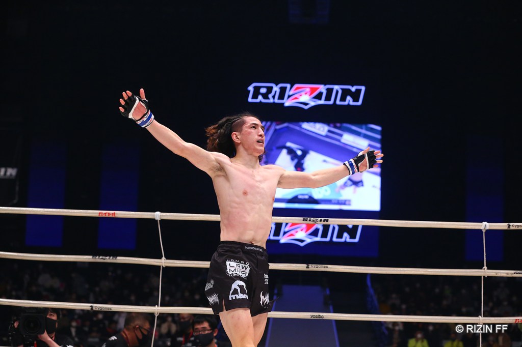 Naoki Inoue walks across the RIZIN ring with his arms up in the air.