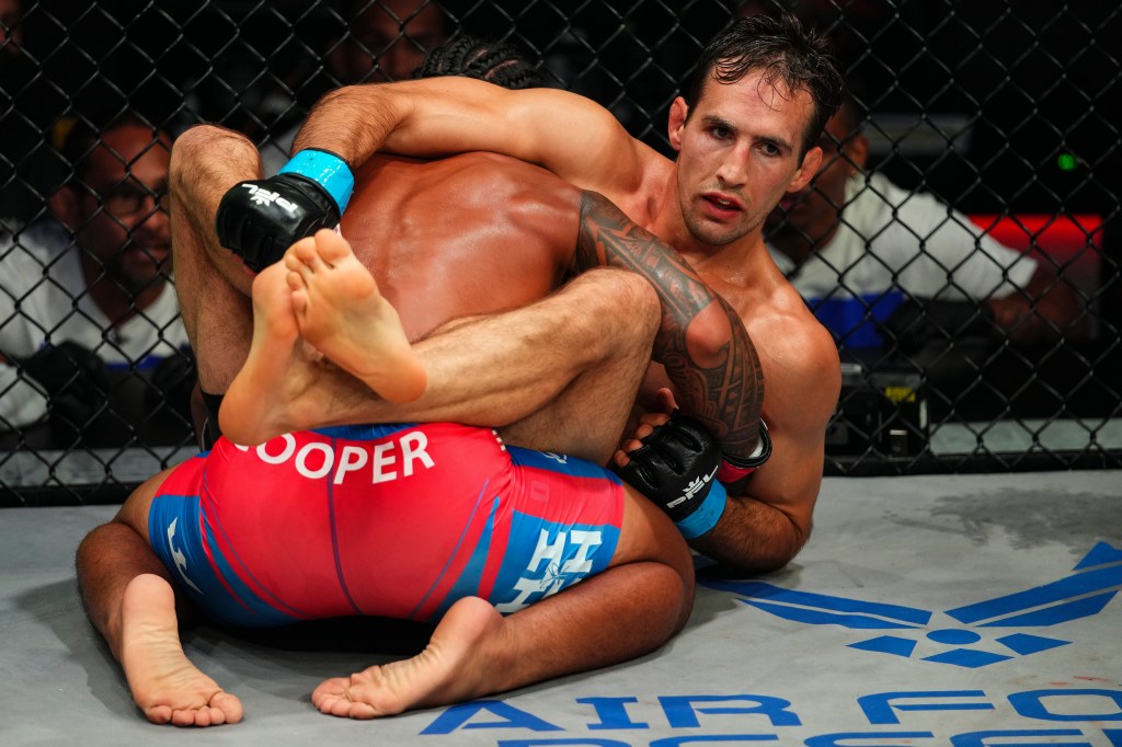 Ray Cooper III sits in the full guard of Rory MacDonald, who looks visibly fatigued.