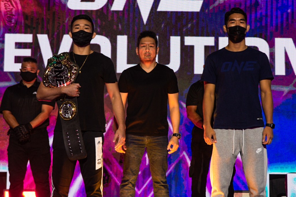 Christian Lee and Ok Rae Yoon face a camera at a ceremonial face-off.