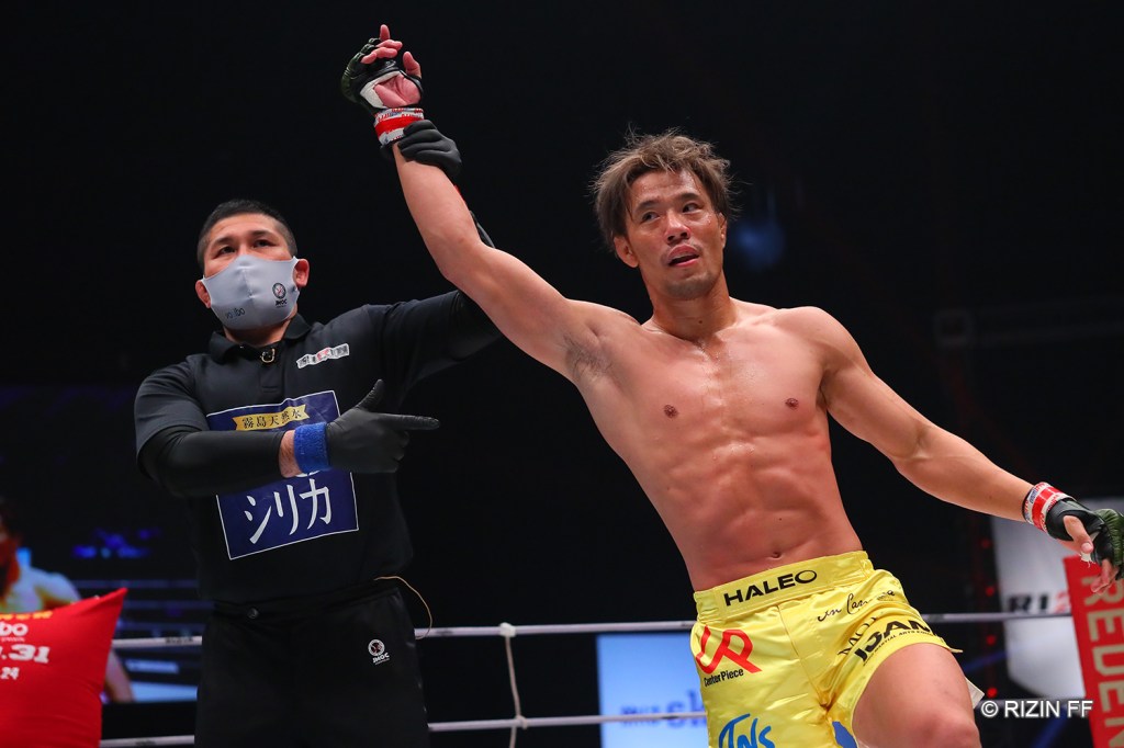 Masanori Kanehara gets his arm raised by a referee.