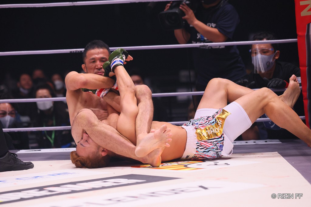 Daisuke Nakamura attempts to extend the arm of Suguru Nii in an armbar submission.