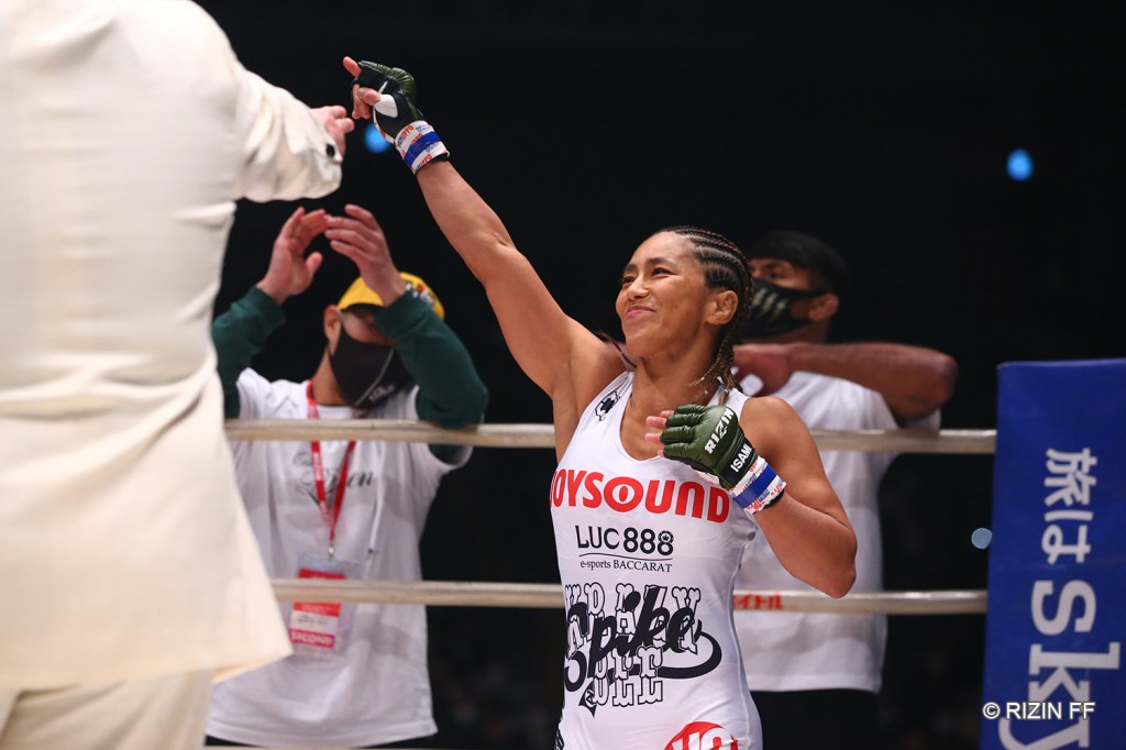 Miyuu Yamamoto raises her arm while standing in the corner of a RIZIN ring.