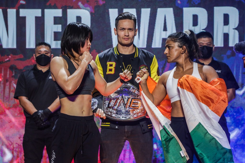 Stamp Fairtex and Ritu Phogat face off at a ceremonial weigh-in event.
