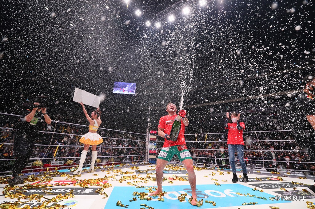Hiromasa Ougikubo sprays a bottle of champagne into the air while standing in the RIZIN ring.