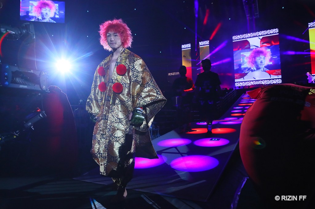 Ulka Sasaki walks to the RIZIN ring, stepping down a ramp while wearing a golden jacket.