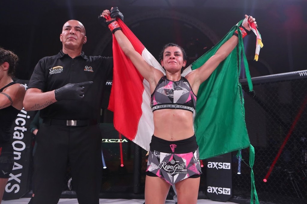 Karina Rodriguez gets her arm raised in the Invicta FC cage while holding the flag of Mexico.
