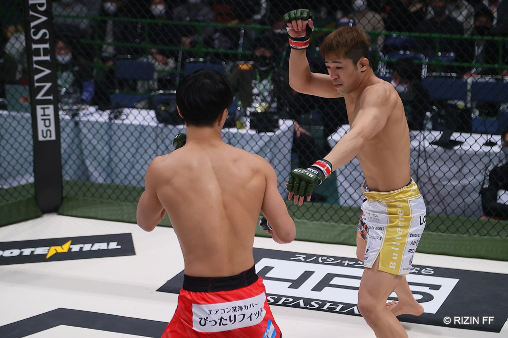 Kotetsu Hara points an arm out at Takuma Uchiyama during a fight in the RIZIN cage.