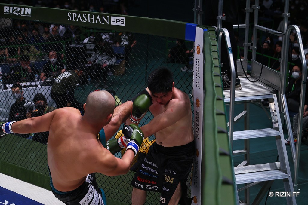 Mountain Ryugo throws a head kick to Katsutoshi Sasadi in a corner of the RIZIN cage.