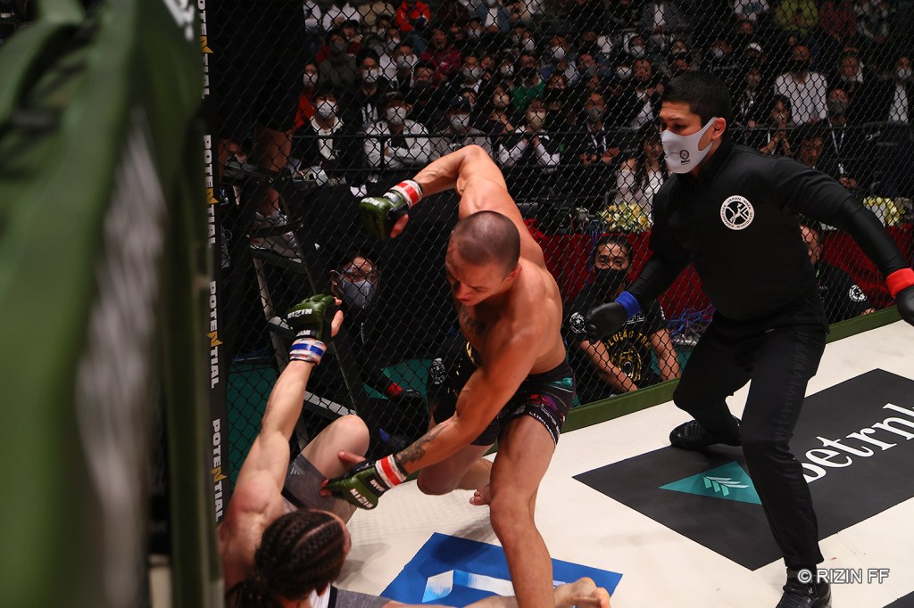 Luiz Gustavo throws a punch to a grounded Yusuke Yachi.