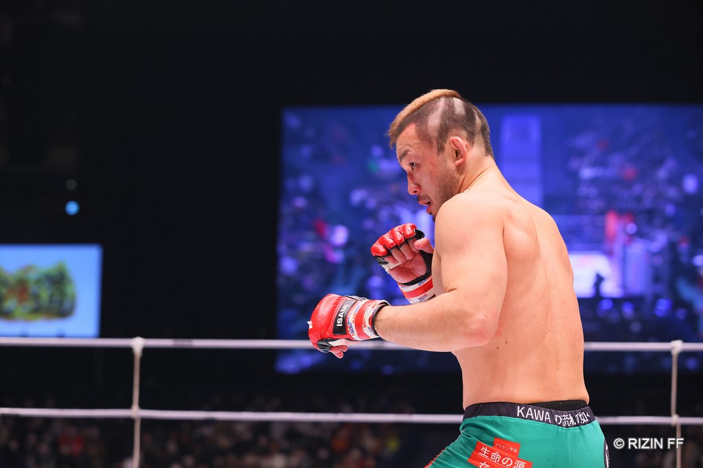 Hiromasa Ougikubo looks focused in a fighter stance while inside the RIZIN cage.