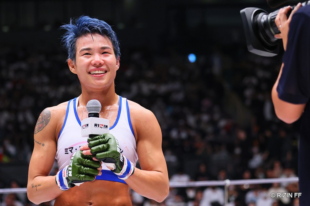 Park Si-woo smiles while holding a microphone in the RIZIN ring.